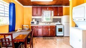 A compact kitchen with wooden cabinets, a microwave, a stove, and a refrigerator. - Chalk Sound Lagoon Cottage with Kayak Dock (Providenciales)