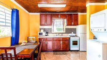 A compact kitchen with wooden cabinets, a microwave, a stove, and a refrigerator.