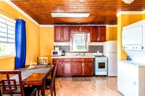 Una cocina compacta con armarios de madera, un microondas, una estufa y un refrigerador.
