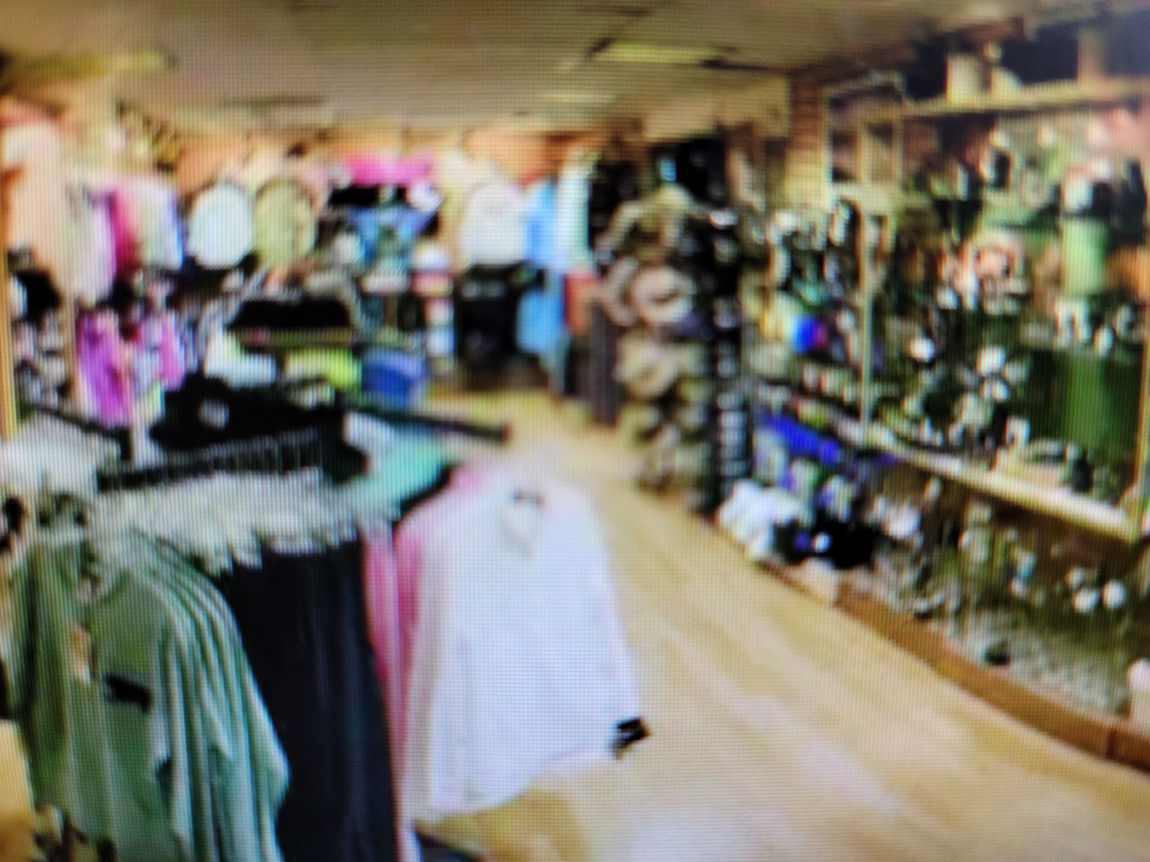 Interior de una tienda con percheros y estanterías llenas de diferentes artículos.