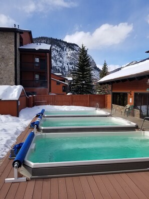 A pool area with two hot tubs, wooden deck, and a mountain backdrop. - Mountainside Retreat - Sleeps 4 (Frisco)