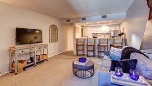 A living room with a TV, a small dining area with stools, and a kitchen in the background. - Mountainside Retreat - Sleeps 4 (Frisco)