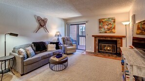 A living room with a fireplace, a sofa, a chair, and a coffee table. - Mountainside Retreat - Sleeps 4 (Frisco)