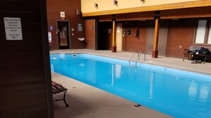 A swimming pool with a hot tub, benches, and a wooden building with a sign indicating a maximum of four persons at a time in the hot tub. - Mountainside Retreat - Sleeps 4 (Frisco)