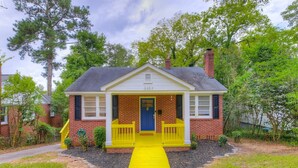 A two-story house with a yellow front porch and a blue door. - Charming Earlewood Cottage - Minutes from Downtown (Columbia)