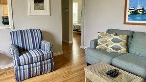 A living room with a striped armchair, a grey sofa, and a wicker coffee table.