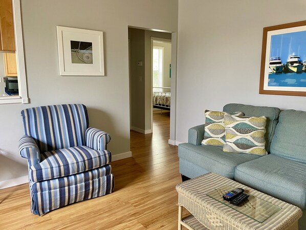 A living room with a striped armchair, a grey sofa, and a wicker coffee table. - Old Florida Style, Dockage, Swimming Pool (shared), just 20 miles from Key West (Cudjoe Key)