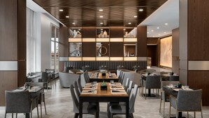 A modern dining area with multiple tables and chairs, a central decorative wall, and a view of the outside. - AC Hotel Bozeman Downtown (Bozeman)