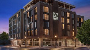 A modern hotel building with a prominent AC Hotels Marriott sign, large windows, and a well-lit entrance area. - AC Hotel Bozeman Downtown (Bozeman)