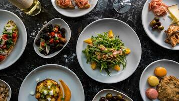 A variety of dishes on plates, including salads, meats, and pastries, arranged on a dark surface.