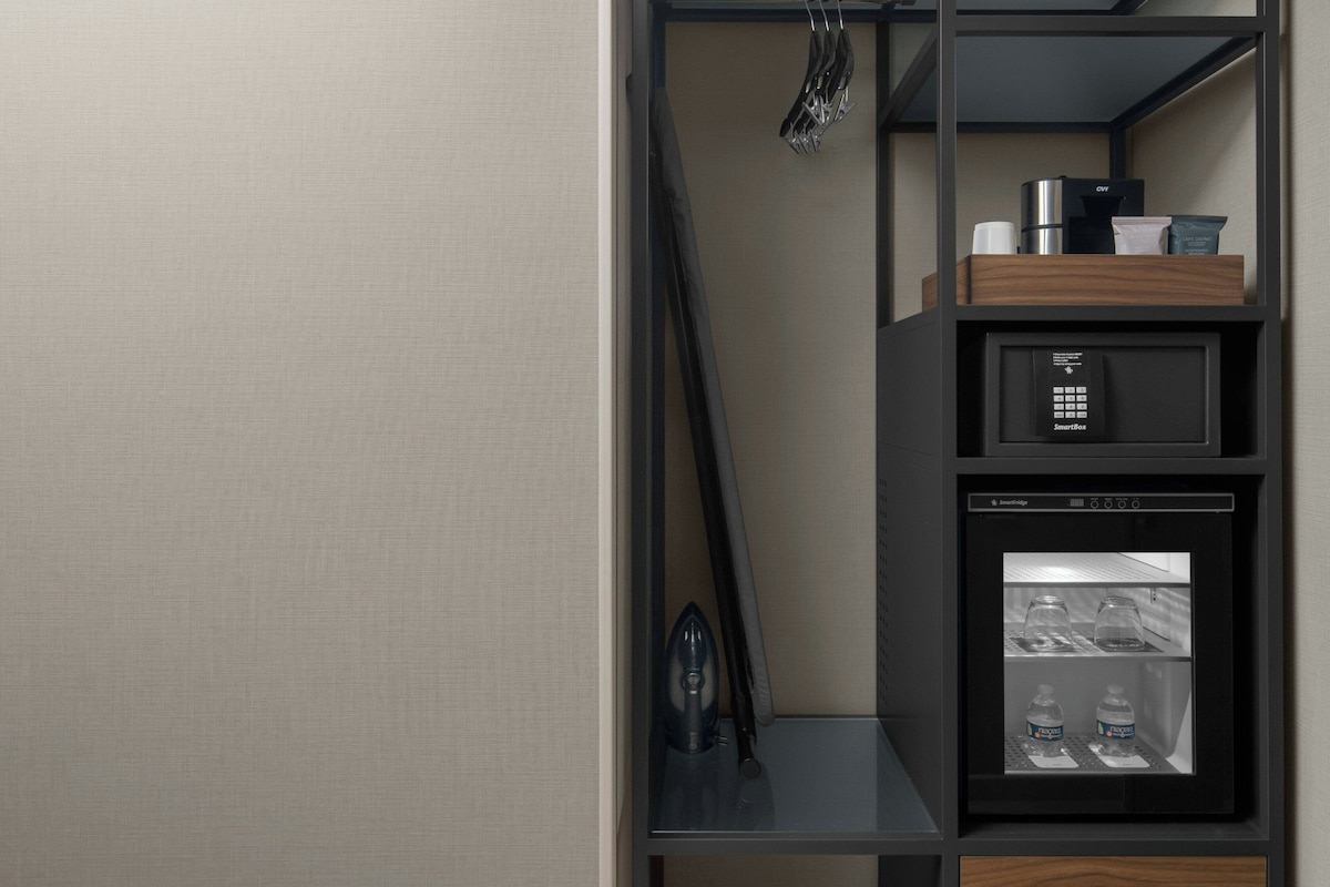 A modern kitchen with a built-in coffee machine, a microwave, and a refrigerator.
