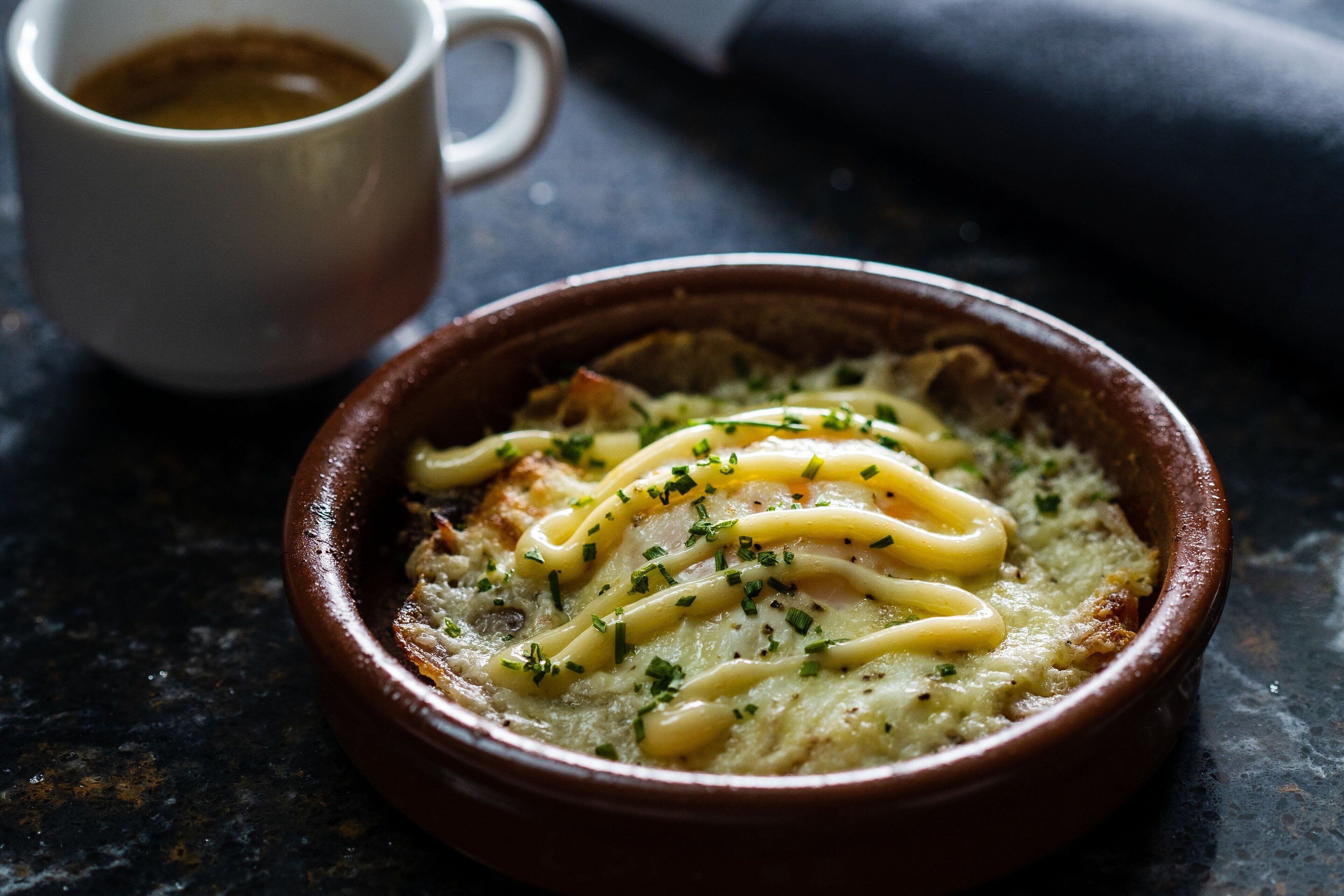 A bowl of food with a cup of coffee beside it.
