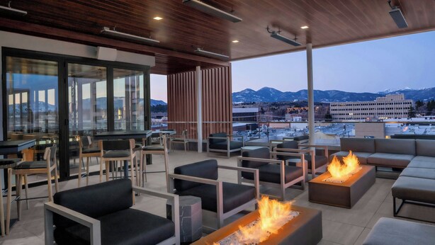 A modern outdoor seating area with fire pits and a view of mountains. - AC Hotel Bozeman Downtown (Bozeman)