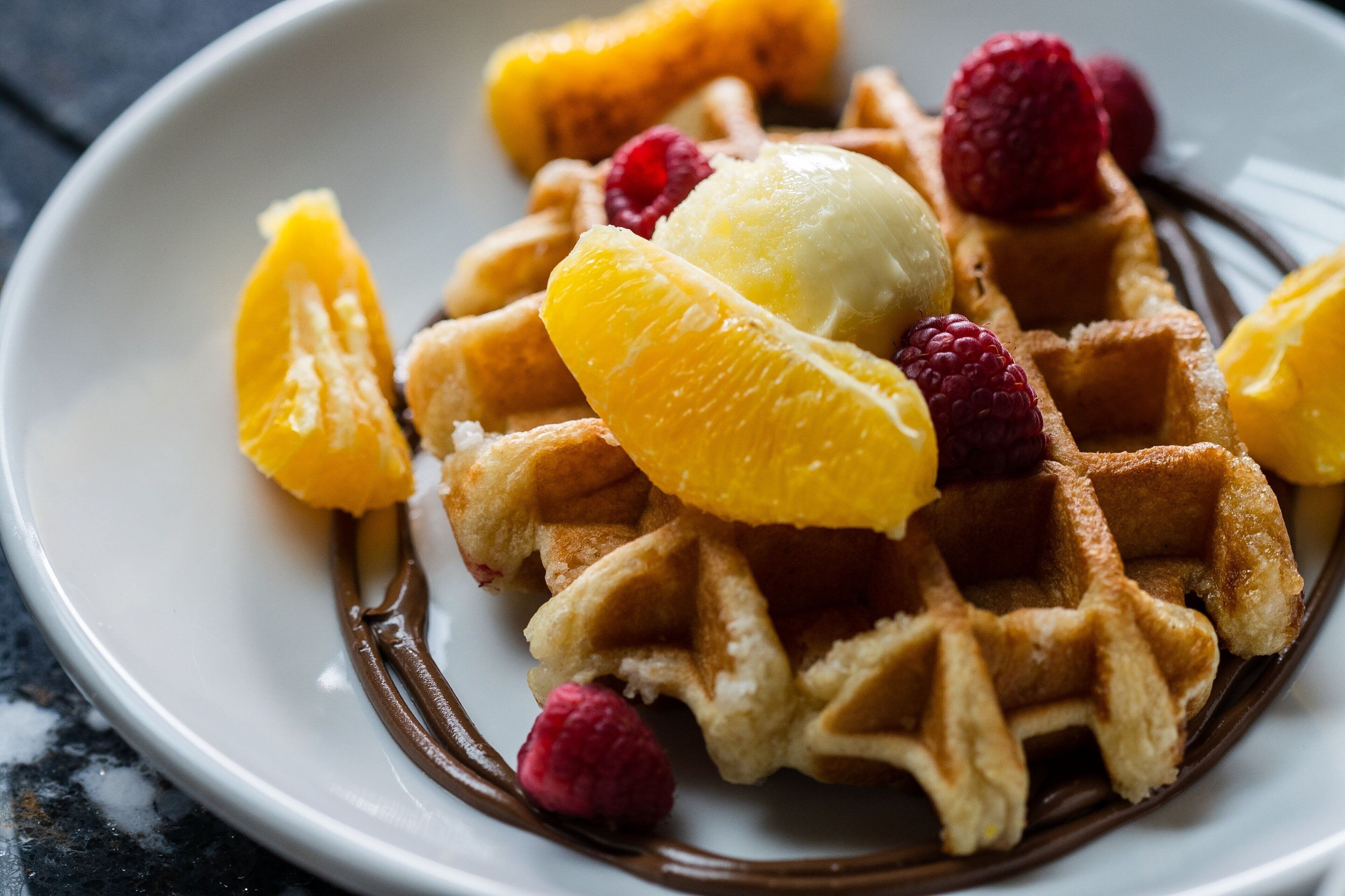 Un plato de waffles cubierto de fruta y helado.