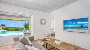 A modern living room with a view of a pool and beach. - Colibri Trotteur (Le Diamant)