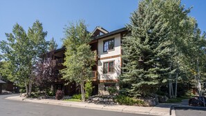 Un immeuble de deux étages avec une façade en pierre, de grandes fenêtres et un balcon.
