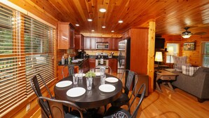 A wooden cabin interior with a dining area, kitchen, and living space.