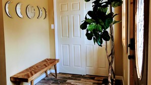 A hallway with a wooden bench, a white door, and a potted plant. - Remodeled 1890 Home with Large Fenced Yard  (Trinidad)