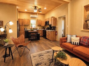 A compact kitchen with wooden cabinets, a central island, and a ceiling fan.