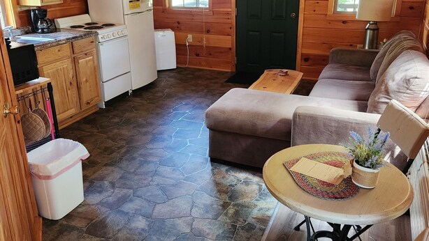 Interior acolhedor de uma cabana, com cozinha, área de refeições e espaço para sentar.