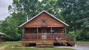 A wooden cabin named "Turtle Rock" with a porch, a star decoration, and a small garden area. - Turkey Roost At Creekside Resort (Clearville)