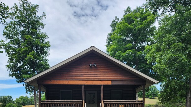 Une cabane en bois avec une véranda et un foyer extérieur.