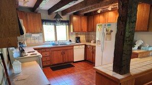 Eine Küche mit Holzausstattung, einem weißen Kühlschrank, einem Herd und einem Spülbecken.
