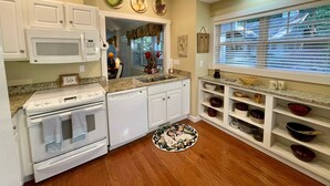 A kitchen with white cabinets, a granite countertop, a stove, a dishwasher, and a window with blinds.