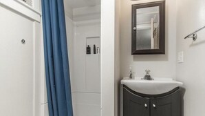 Ein Badezimmer mit einem weißen Waschbecken, einem dunklen Schrank und einem Spiegel darüber.