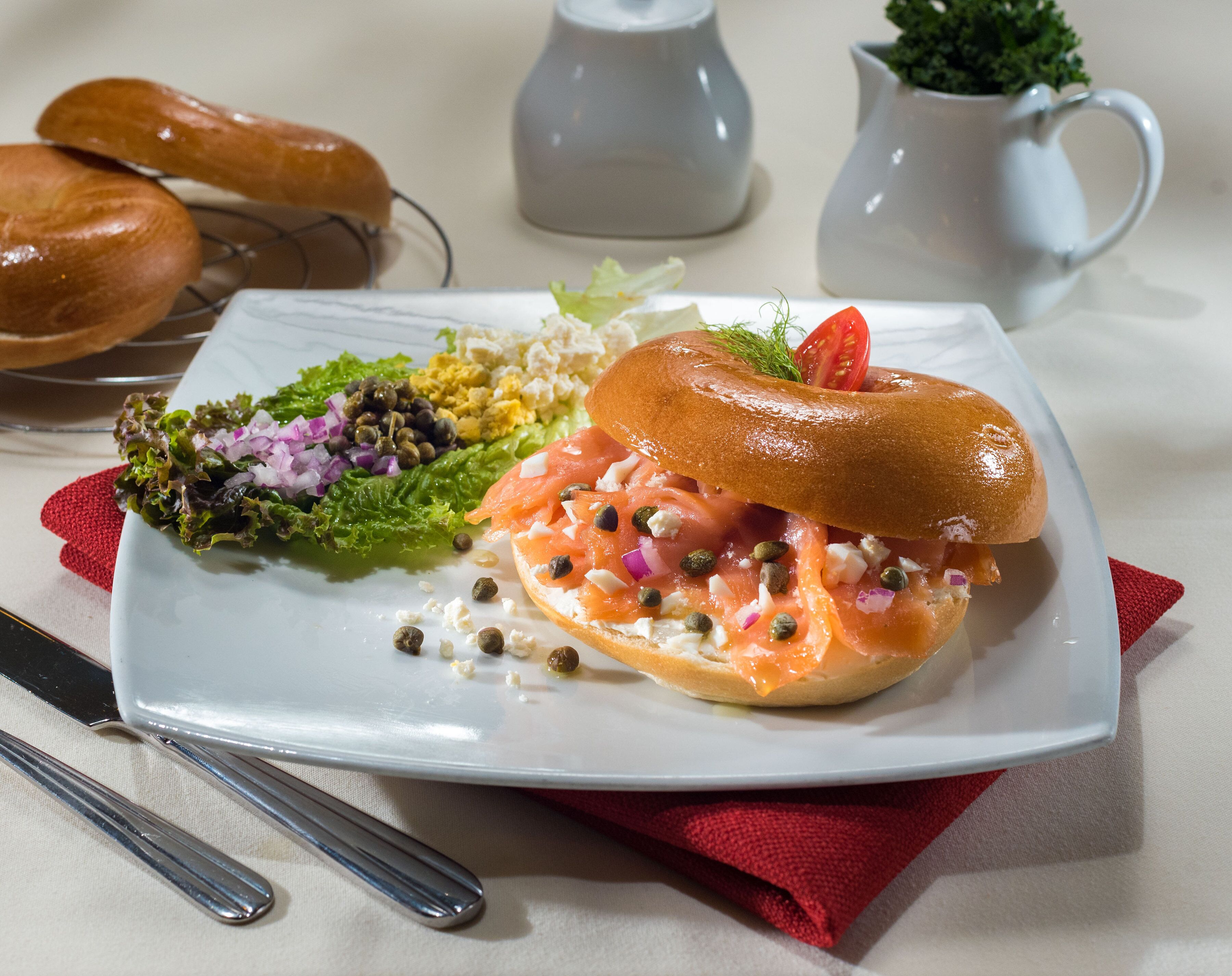 A plate with a sandwich, salad, and a pitcher of milk.