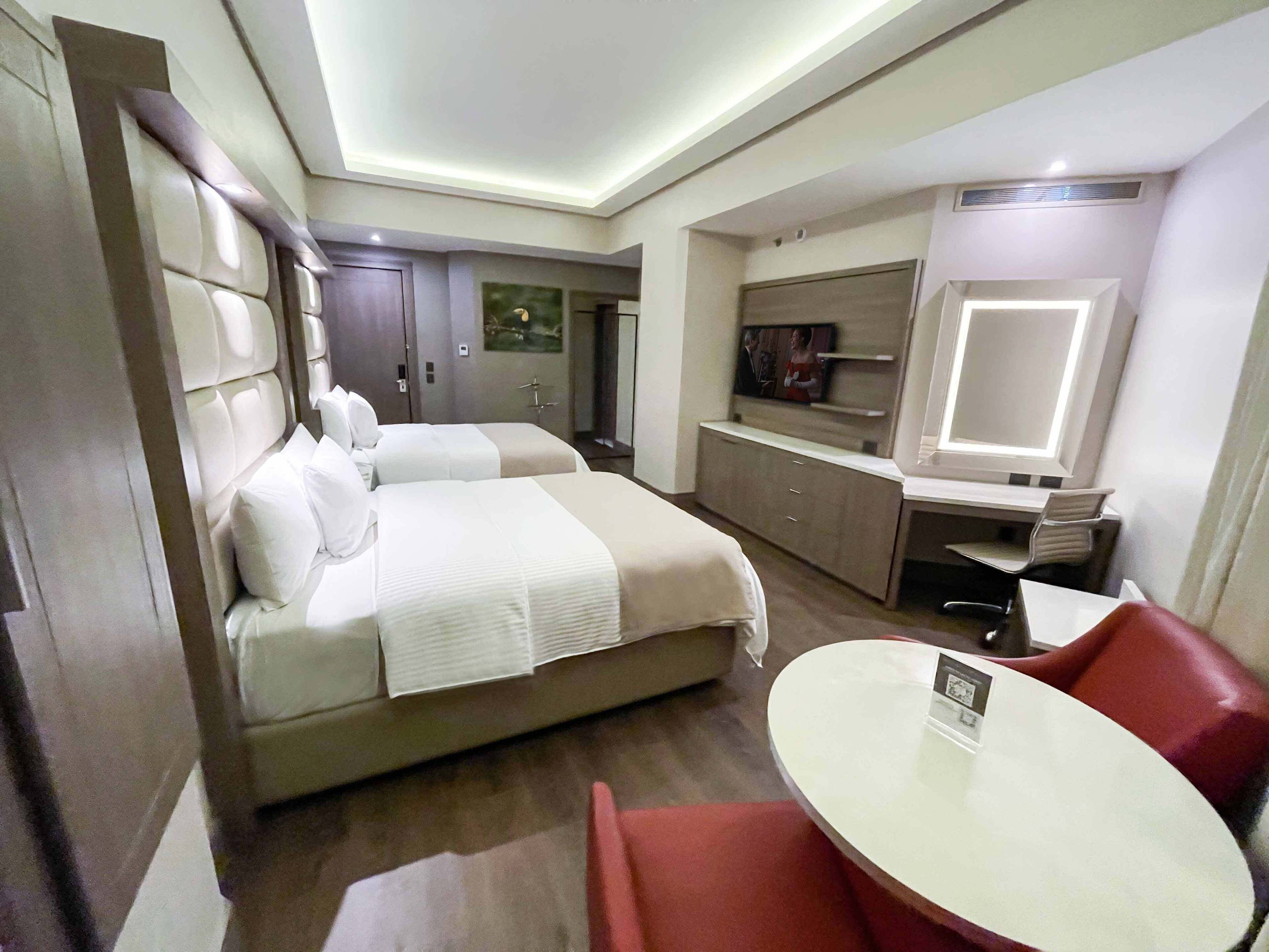 Una habitación de hotel con dos camas, un escritorio, una silla y un televisor.