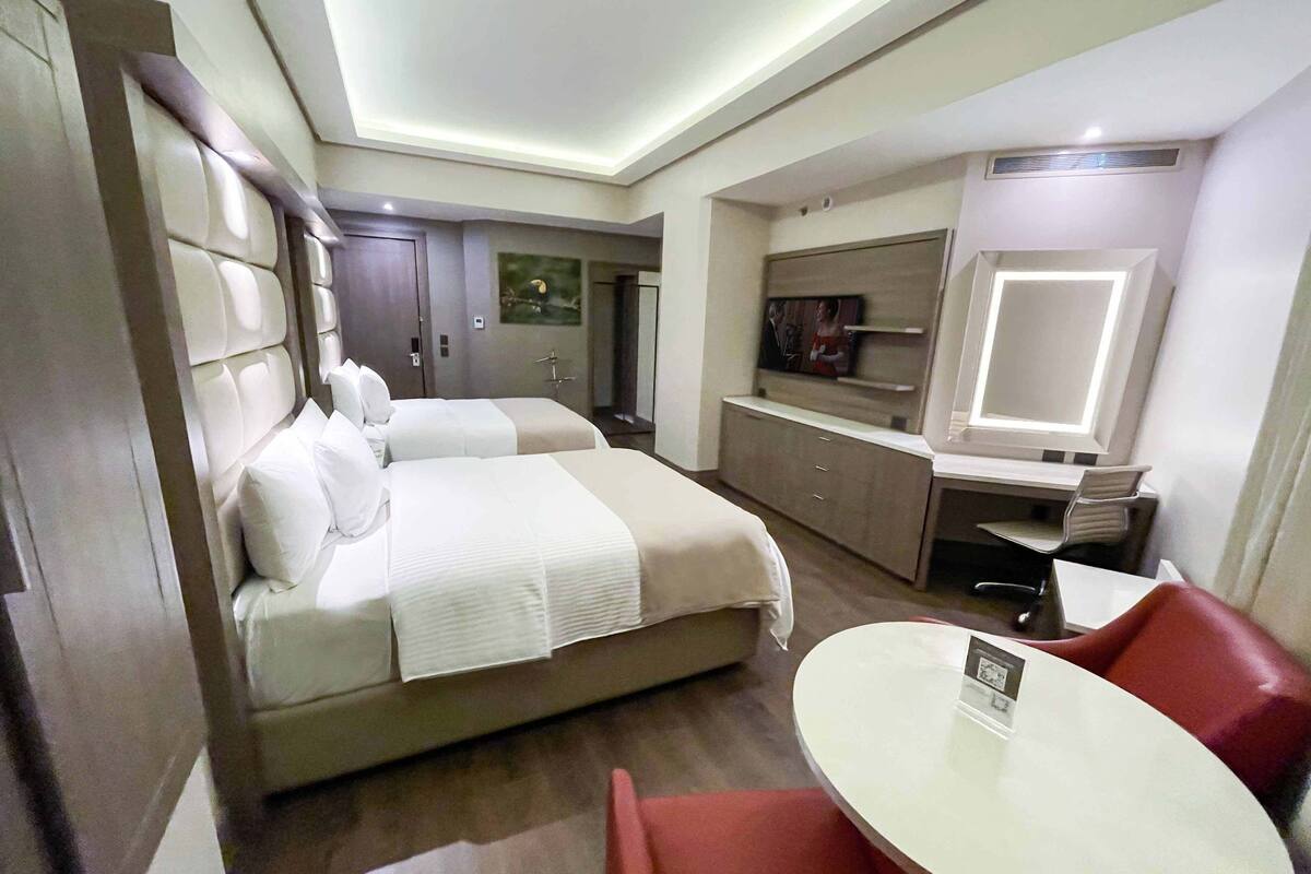 Een hotelkamer met twee bedden, een bureau, een stoel en een televisie.