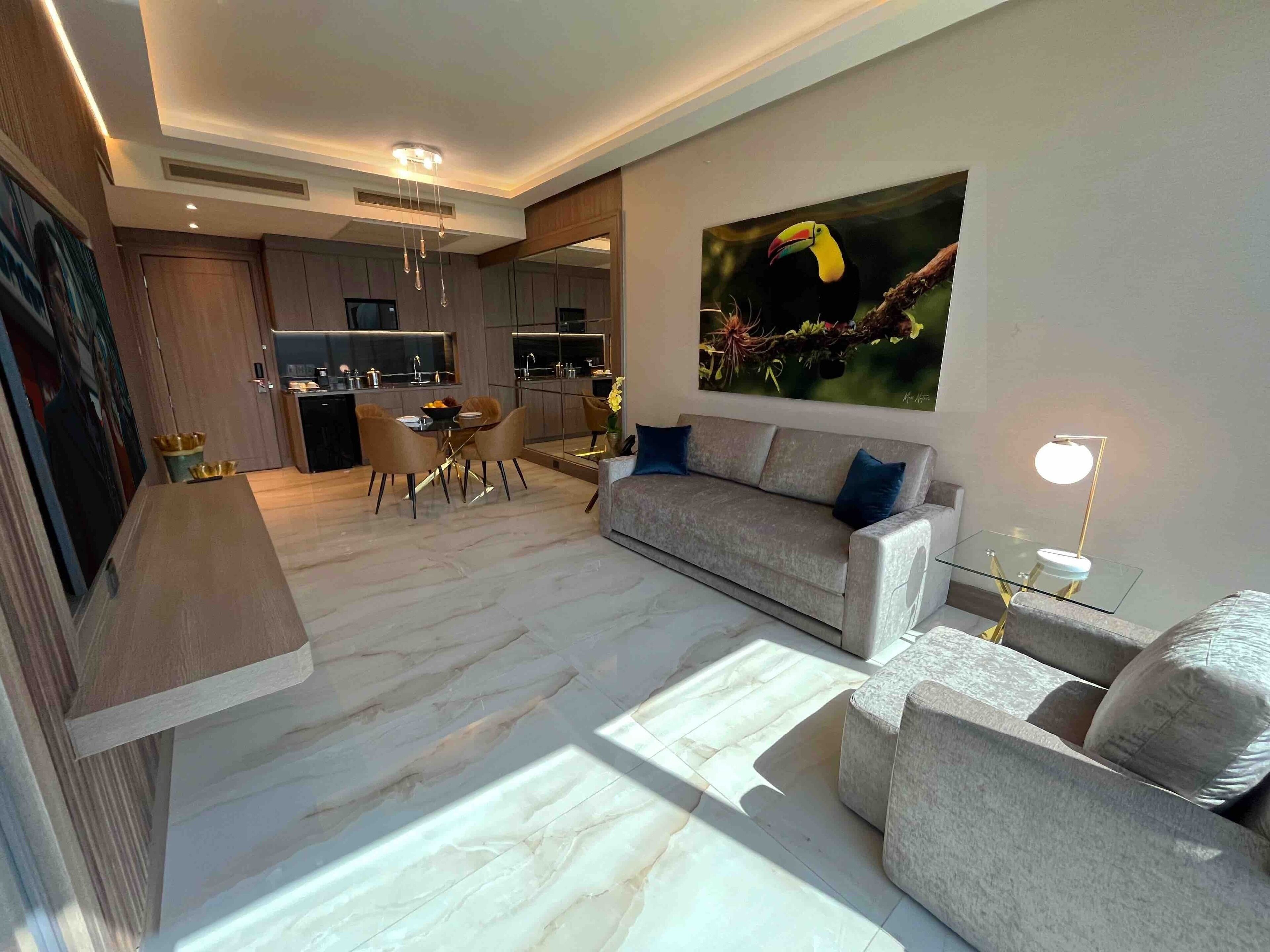 A modern living room with a sofa, coffee table, and a dining area with chairs.