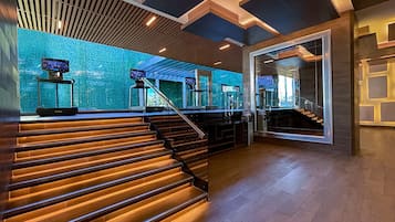 Un moderno vestíbulo de hotel con una escalera, un mostrador de recepción y un amplio ventanal con vistas.