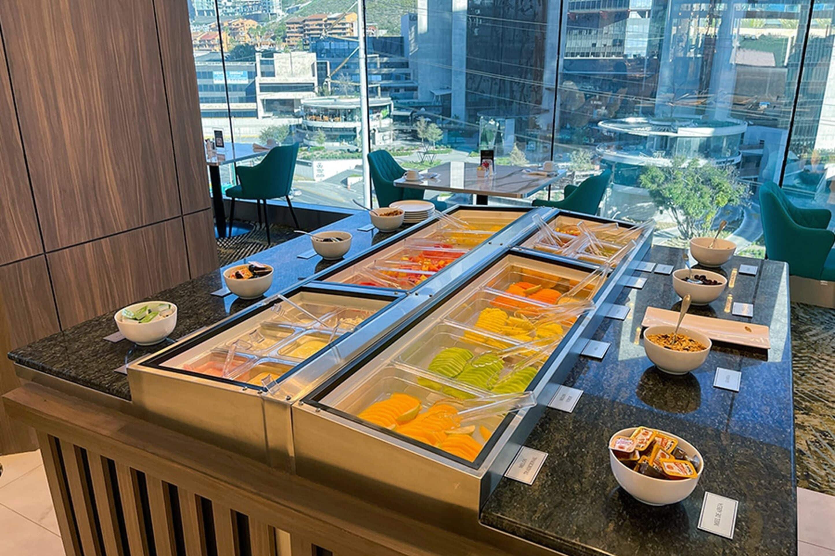 Ein Buffet mit verschiedenen Speisen und Blick auf die Stadt durch große Fenster.