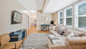 A living room with a sofa, a coffee table, a TV, and a patterned rug.