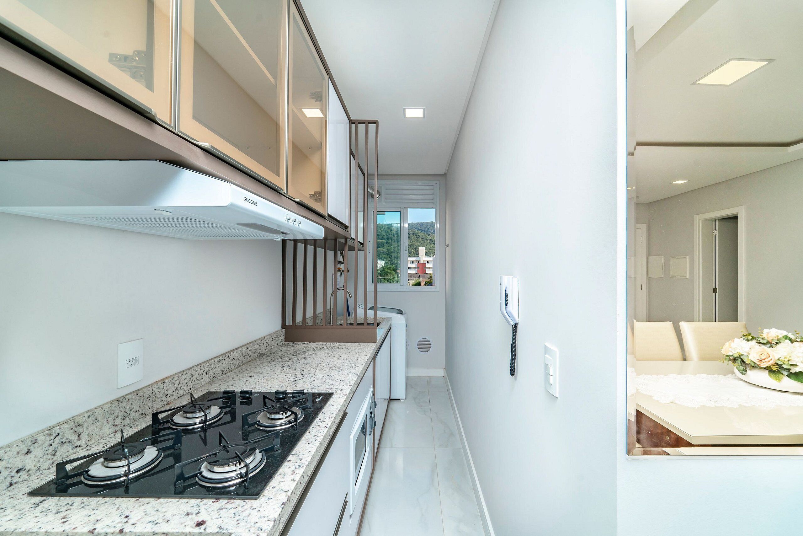 A narrow kitchen with a gas stove, white cabinets, and a view to the dining area.