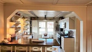 A kitchen with a central island, white cabinets, and a hanging light fixture. - Twin River Stone Cottage - 7 BR/Sleeps 20 (Norfork)