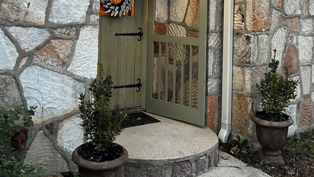 A stone house with a green door, a number sign, and two potted plants. - Twin River Stone Cottage - 7 BR/Sleeps 20 (Norfork)