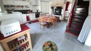A compact kitchen with a dining area, a built-in stove, and a staircase leading to an upper level. - Between Landes and Sauternes, a cosy gîte! (Préchac)