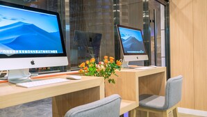 Zwei Apple iMac Computer auf Holztischen mit Tastatur, Maus und einer Blumenvase.
