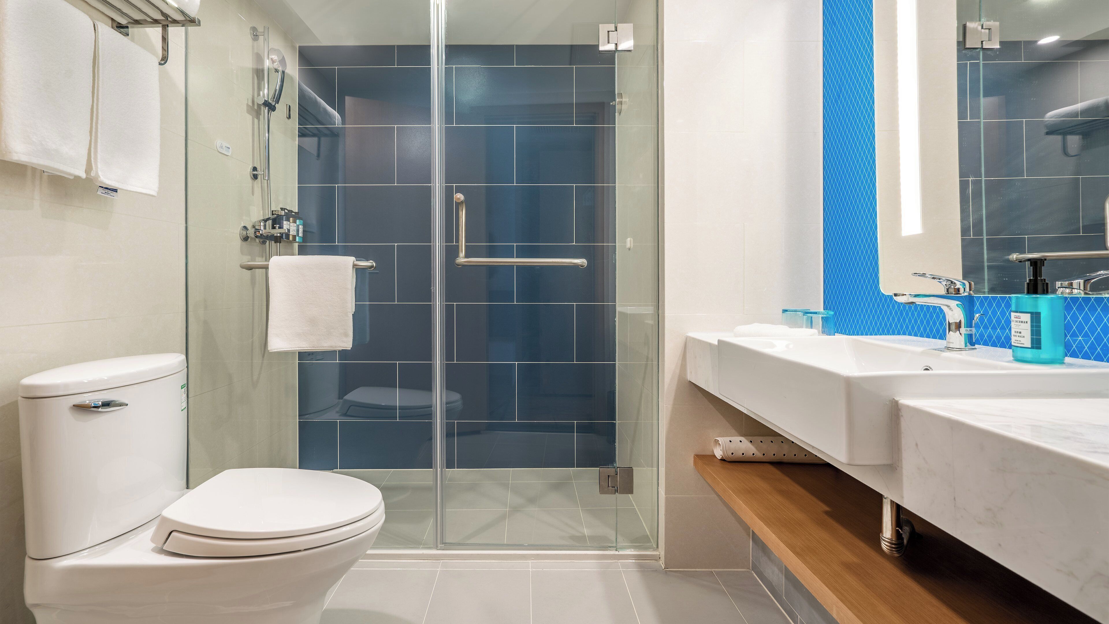 Un bagno moderno con doccia vetrata, un water bianco e un mobile lavabo con specchio.