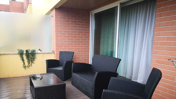 An outdoor patio with wicker furniture, a glass door, and a brick wall. - Apartment with view and pool access 900 meters from the beach (Ovar)