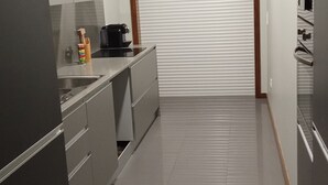 A modern kitchen with grey cabinets, a black coffee machine, and a white countertop. - Apartment with view and pool access 900 meters from the beach (Ovar)