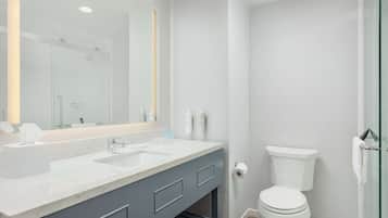 A modern bathroom with a dual sink vanity, a toilet, and a glass shower enclosure.