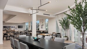 Un comedor moderno con una mesa larga, varias sillas y una planta en maceta.