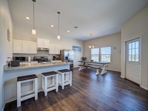 Enjoy meals in this kitchen and dining area with white cabinetry, stainless steel appliances, and a granite countertop.