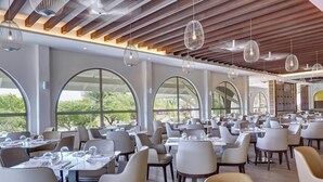 Un restaurante con mesas redondas, sillas e iluminación colgante.