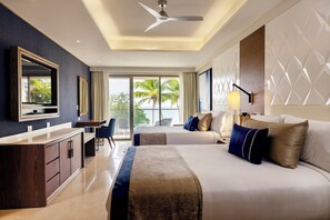 A modern hotel room with a large bed, a desk, and a view of palm trees.