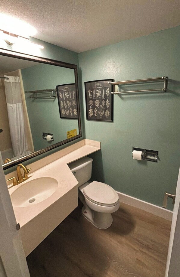 Un baño con lavamanos, inodoro y espejo.